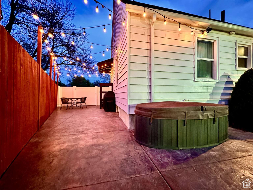 Property exterior at twilight with a fenced backyard, a patio, and a hot tub