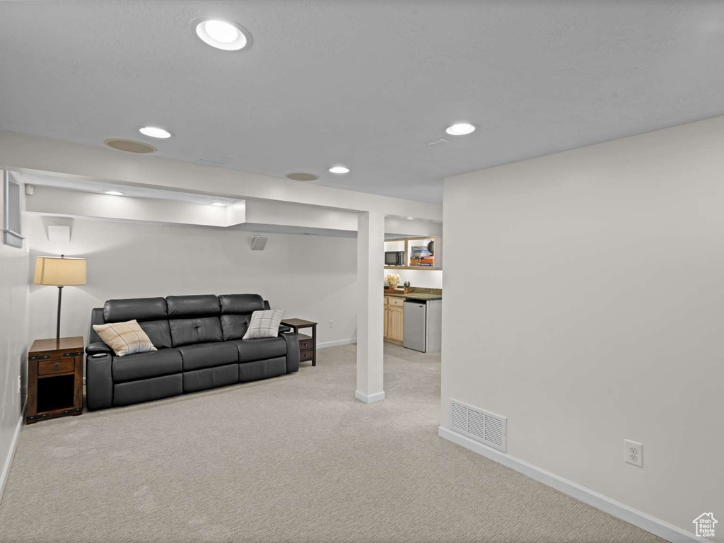 Living area featuring recessed lighting, baseboards, visible vents, and light carpet