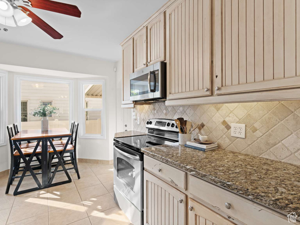 Kitchen with a ceiling fan, tasteful backsplash, light tile patterned floors, stainless steel appliances, and cream cabinetry