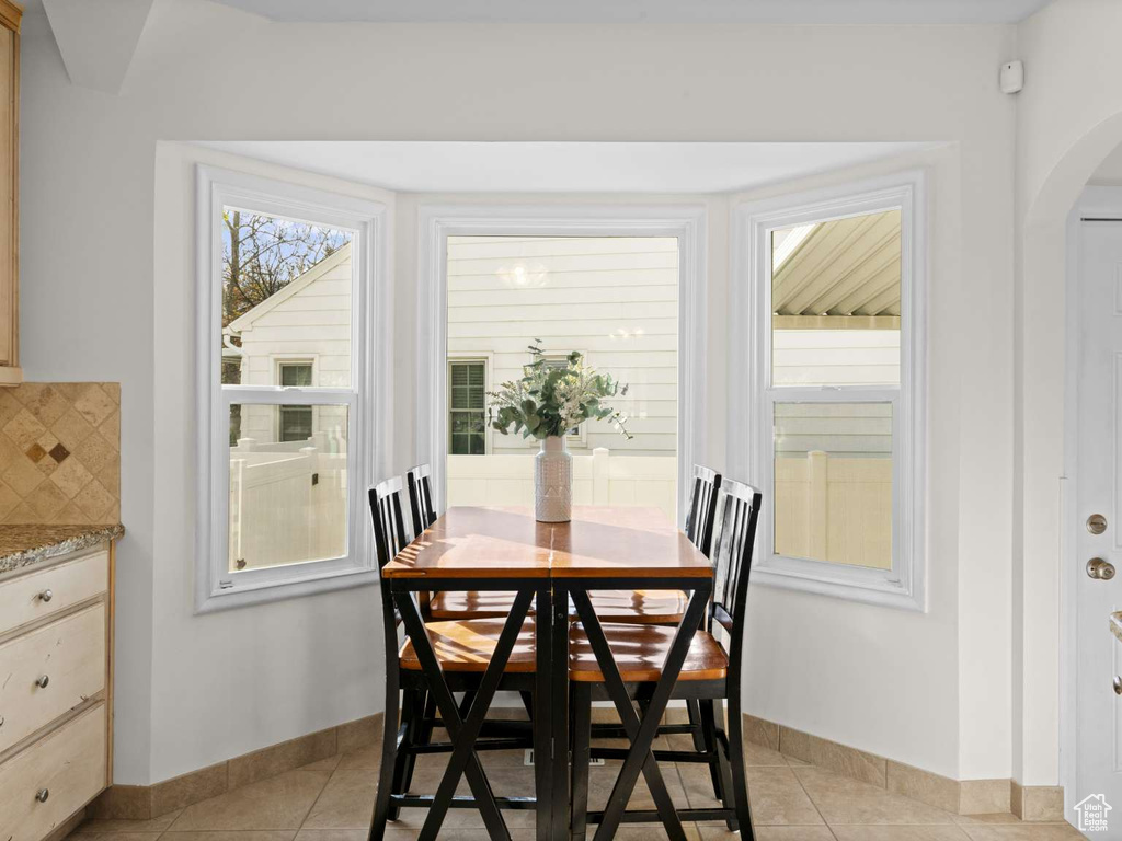 Dining room with baseboards, arched walkways, and light tile patterned floors