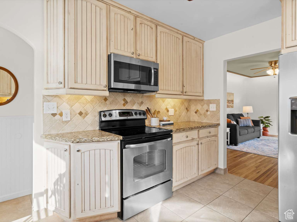 Kitchen with ceiling fan, light tile patterned floors, cream cabinetry, appliances with stainless steel finishes, and backsplash