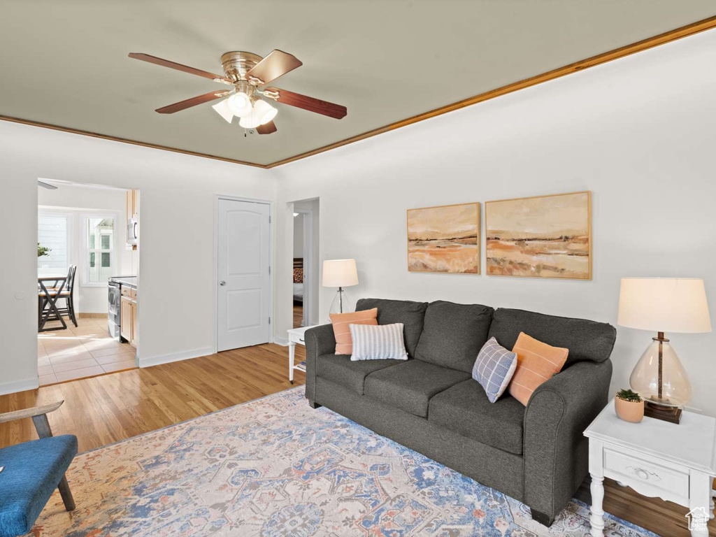 Living room with baseboards, a ceiling fan, and light wood-style flooring
