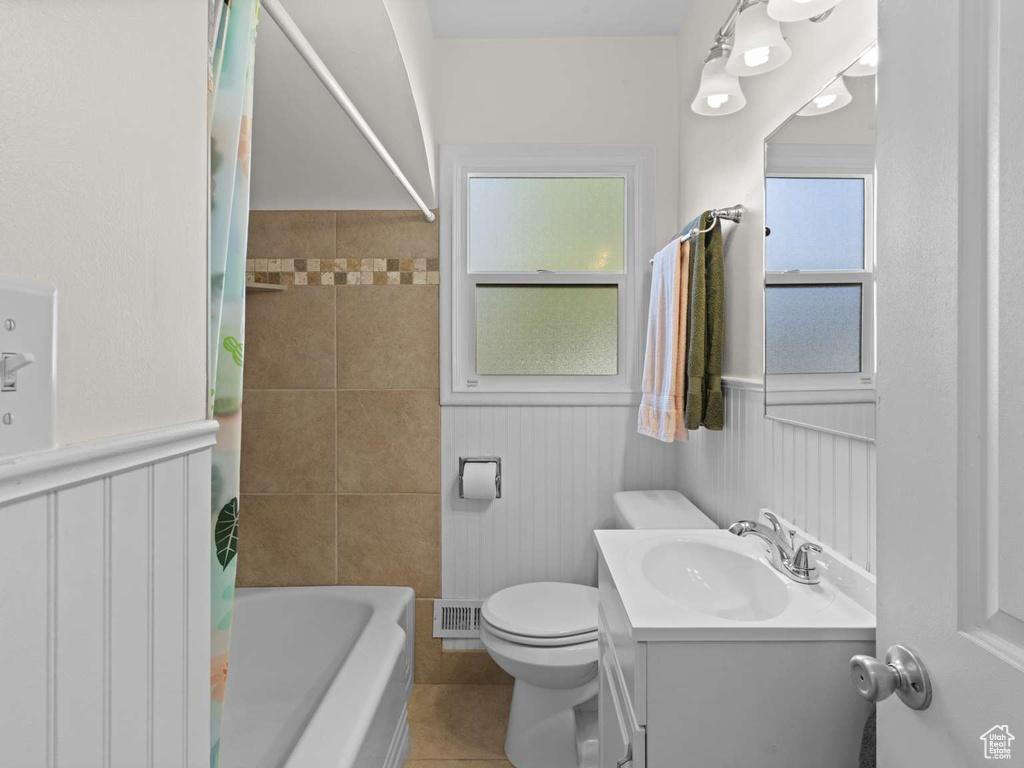 Full bath featuring vanity, visible vents, wainscoting, toilet, and tile patterned floors