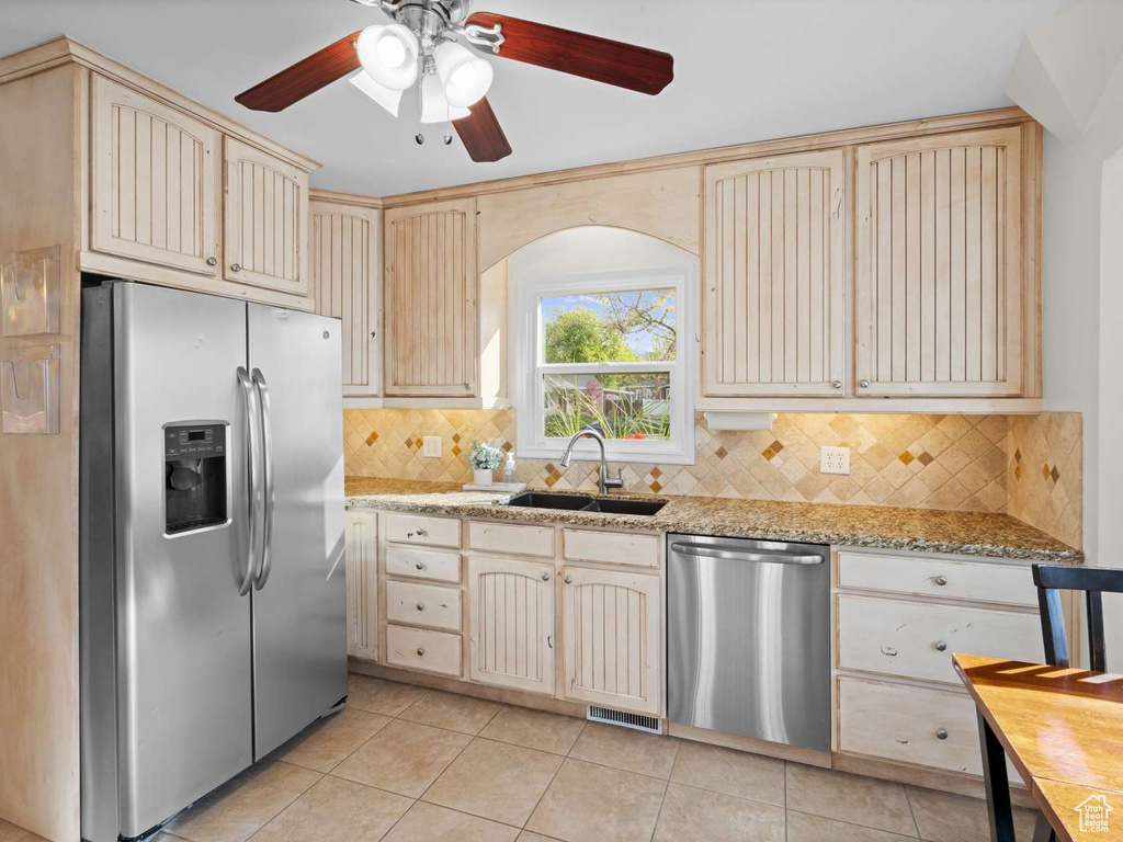 Kitchen featuring a sink, light tile patterned floors, backsplash, and stainless steel appliances