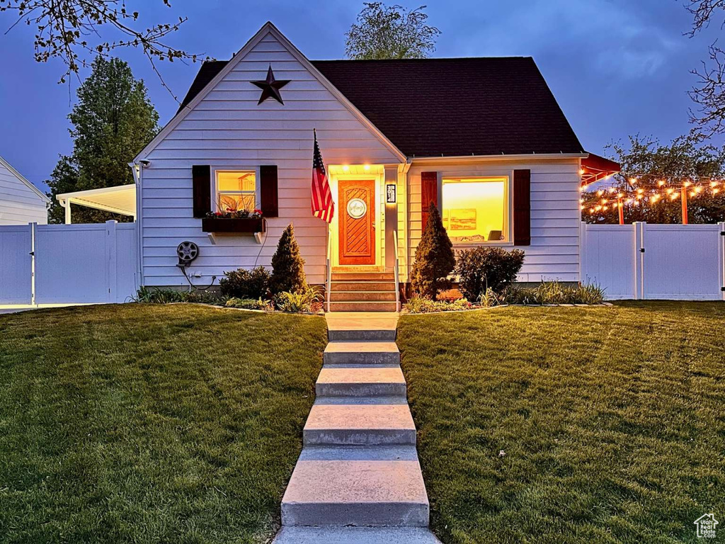Bungalow-style house with entry steps, fence, a gate, and a front yard
