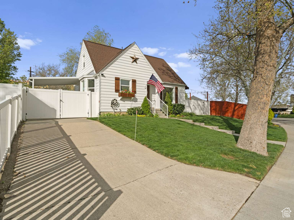 View of front of property featuring driveway, a front yard, roof with shingles, a gate, and fence