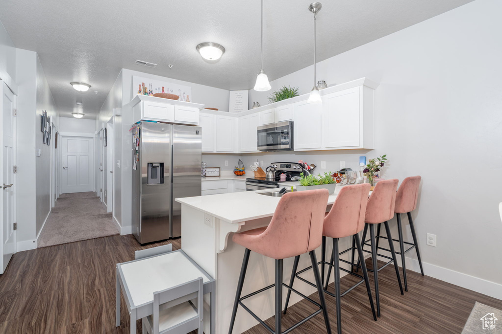 Kitchen with a peninsula, a kitchen bar, dark wood-style floors, and stainless steel appliances