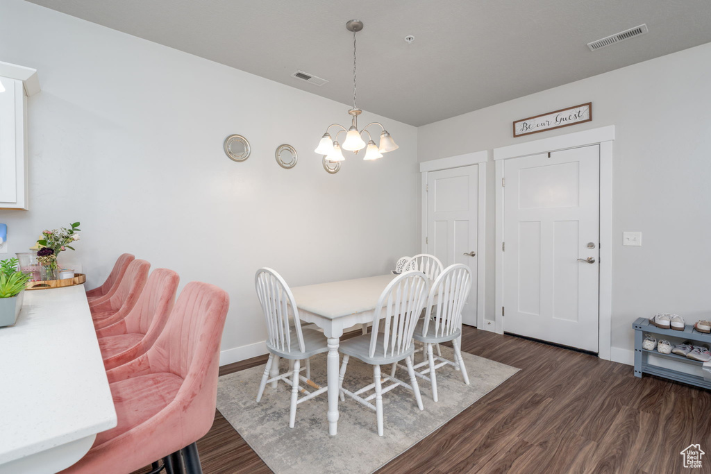Dining area with baseboards, a notable chandelier, dark wood finished floors, and visible vents