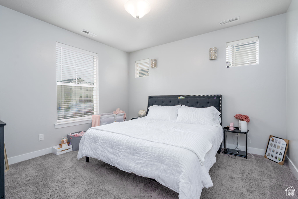 Carpeted bedroom featuring visible vents and baseboards