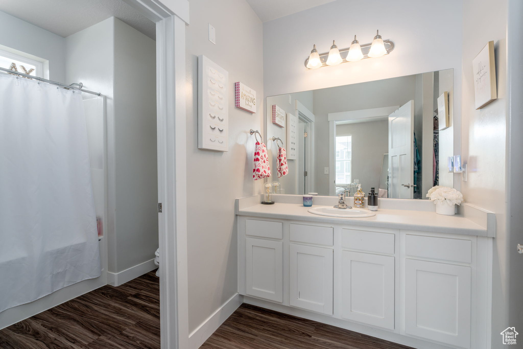 Full bath with toilet, baseboards, wood finished floors, and vanity