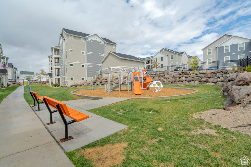 Communal playground featuring a lawn, fence, and a residential view