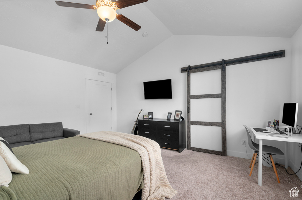 Bedroom featuring light colored carpet, a barn door, ceiling fan, and vaulted ceiling