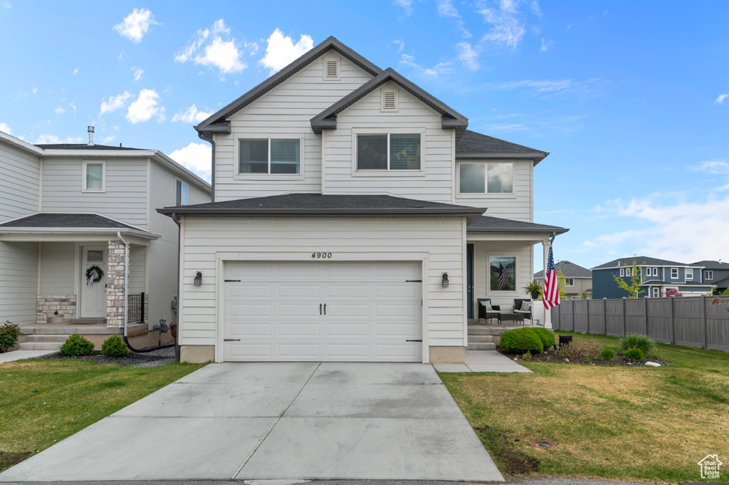 Traditional-style house with fence, a front lawn, a garage, a porch, and driveway