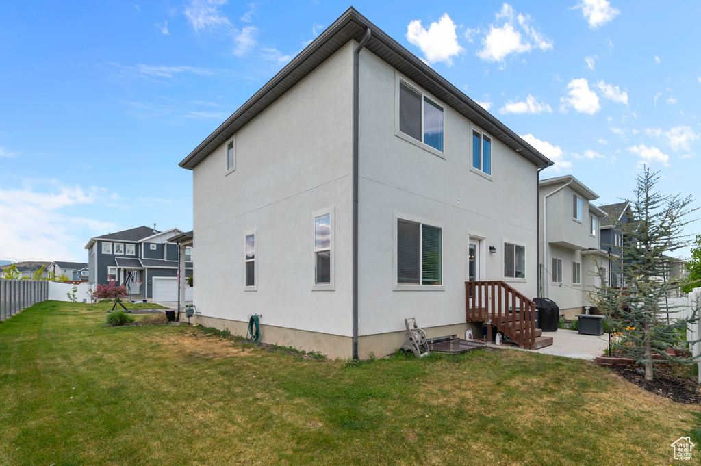 Rear view of house featuring fence, stucco siding, a lawn, and a residential view