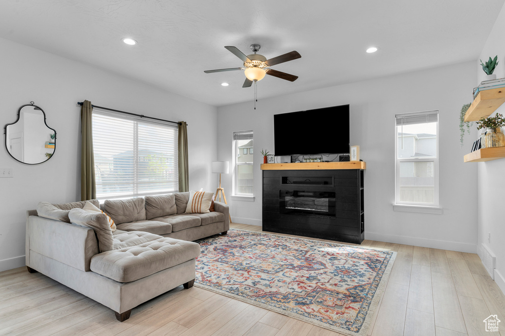 Living area featuring recessed lighting, a ceiling fan, a glass covered fireplace, and wood finished floors