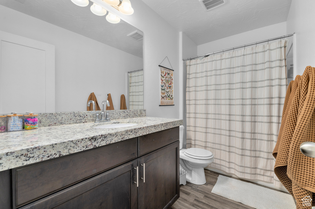 Full bath with visible vents, wood finished floors, toilet, and vanity