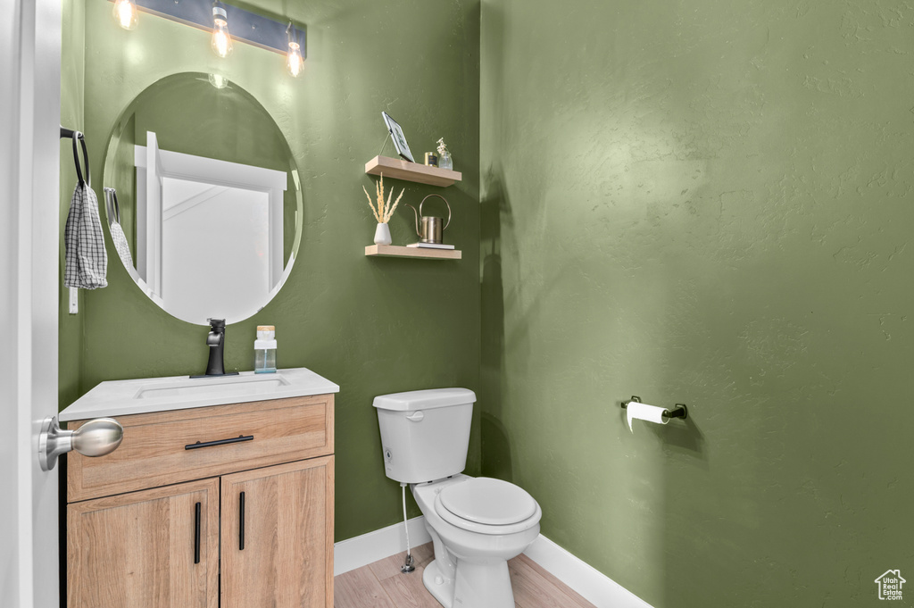 Bathroom with toilet, baseboards, wood finished floors, and vanity