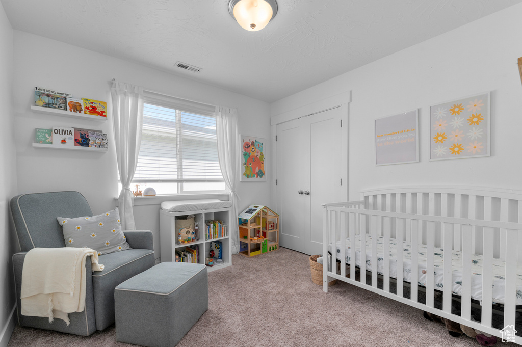 Bedroom with visible vents, carpet flooring, and a crib
