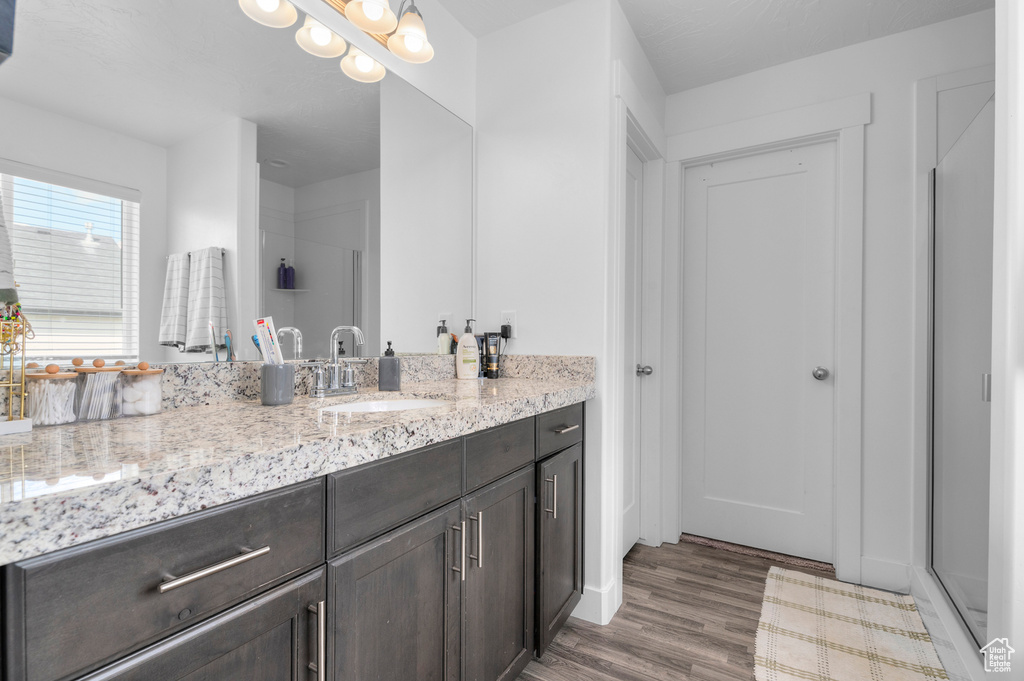 Full bathroom featuring vanity, a shower with door, and wood finished floors