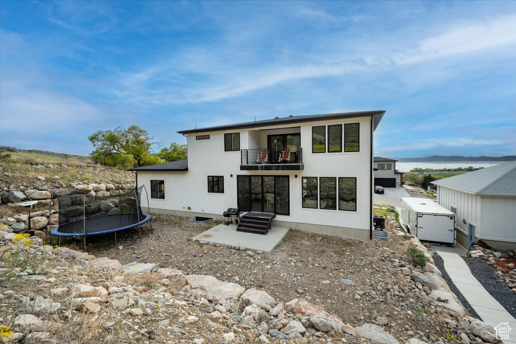 Back of house with a trampoline, stucco siding, and a balcony