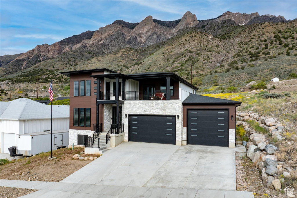 Contemporary house with driveway, a mountain view, a balcony, and stone siding