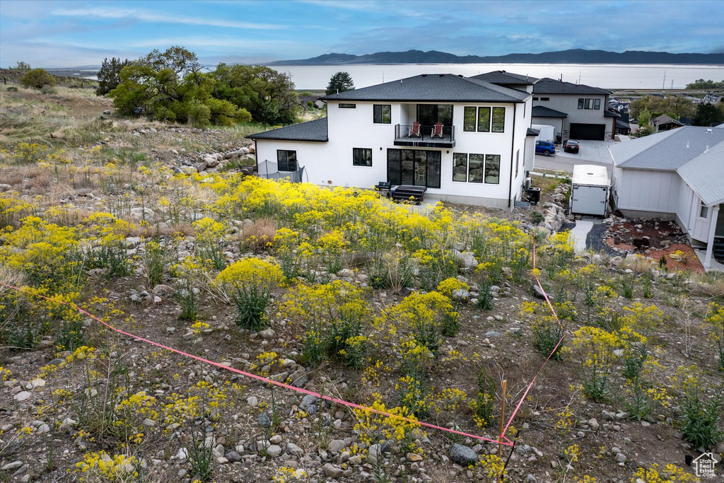 Rear view of property with roof with shingles, stucco siding, a balcony, and a mountain view