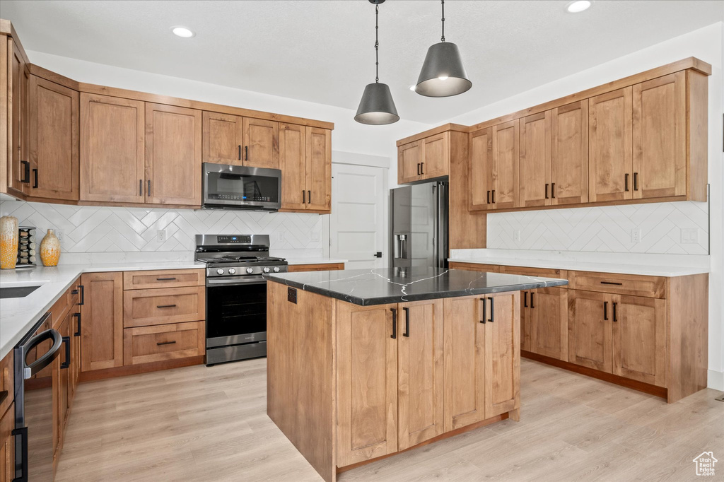 Kitchen with a center island, decorative backsplash, stainless steel appliances, and light wood-style flooring