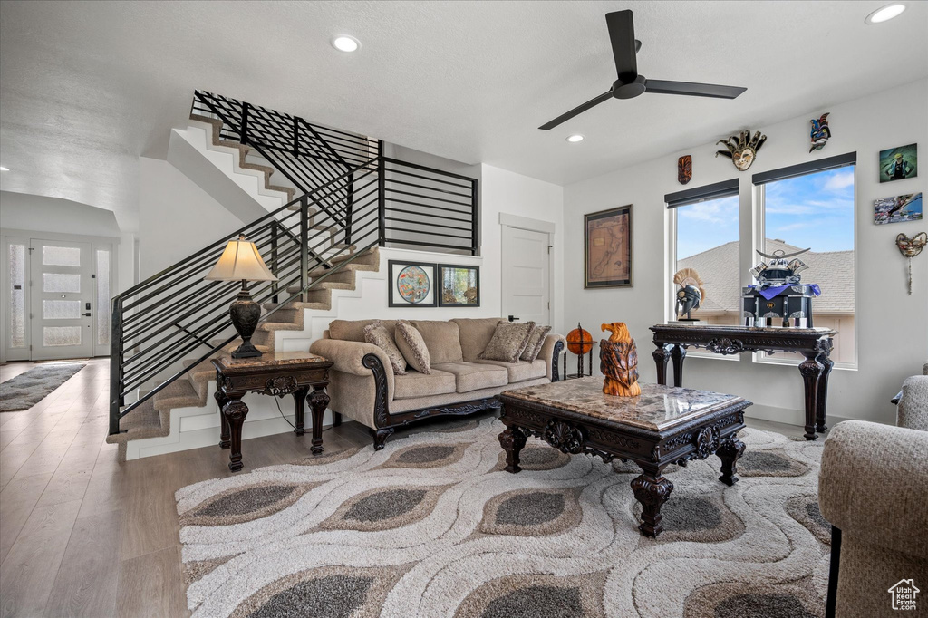 Living area with recessed lighting, a ceiling fan, stairs, and wood finished floors