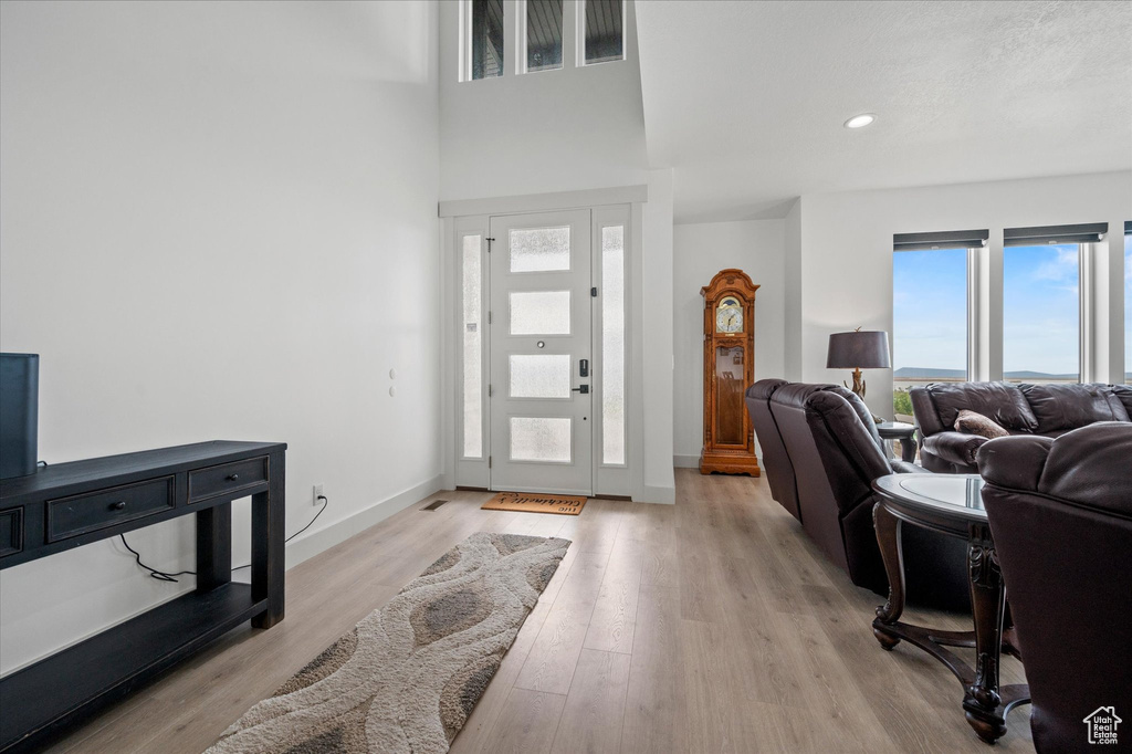 Entryway featuring recessed lighting, baseboards, a high ceiling, and light wood-style floors