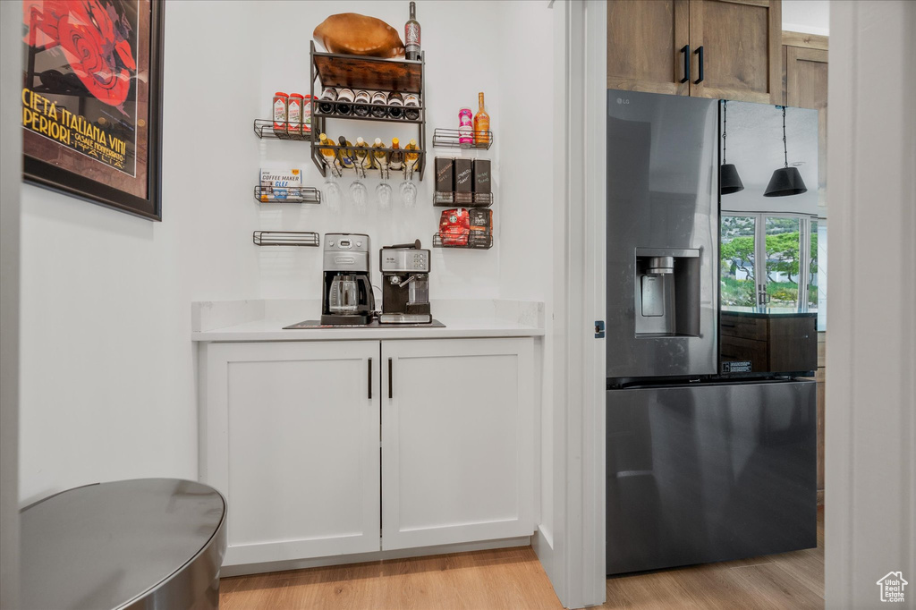 Bar featuring stainless steel fridge with ice dispenser and light wood finished floors