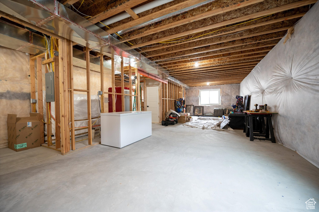 Basement featuring electric panel and fridge