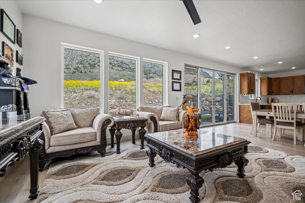 Living area with recessed lighting, a ceiling fan, and light wood-style floors