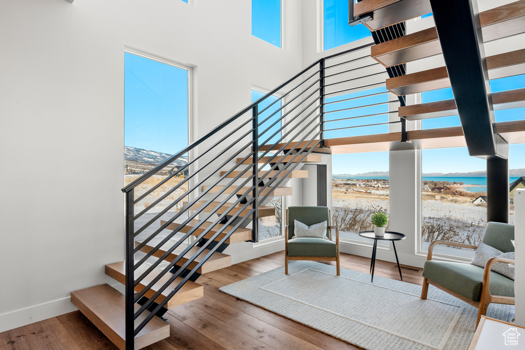 Stairs featuring a water view, baseboards, a wealth of natural light, and wood finished floors