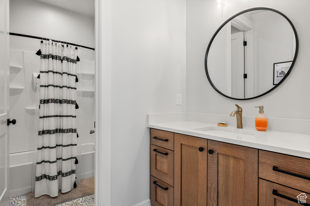 Bathroom featuring shower / bath combo with shower curtain, baseboards, and vanity