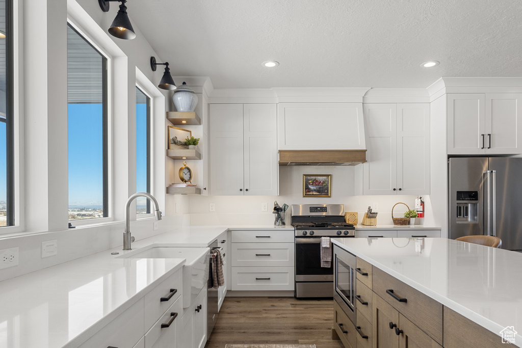 Kitchen with open shelves, wood finished floors, light countertops, white cabinets, and stainless steel appliances