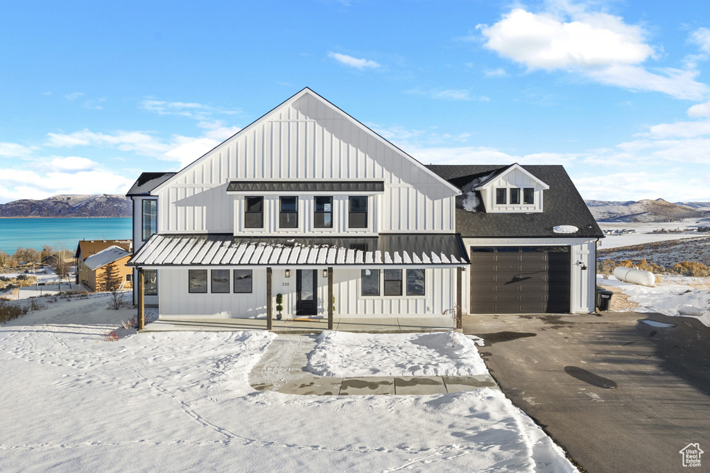 Modern farmhouse with a porch, aphalt driveway, board and batten siding, and a mountain view