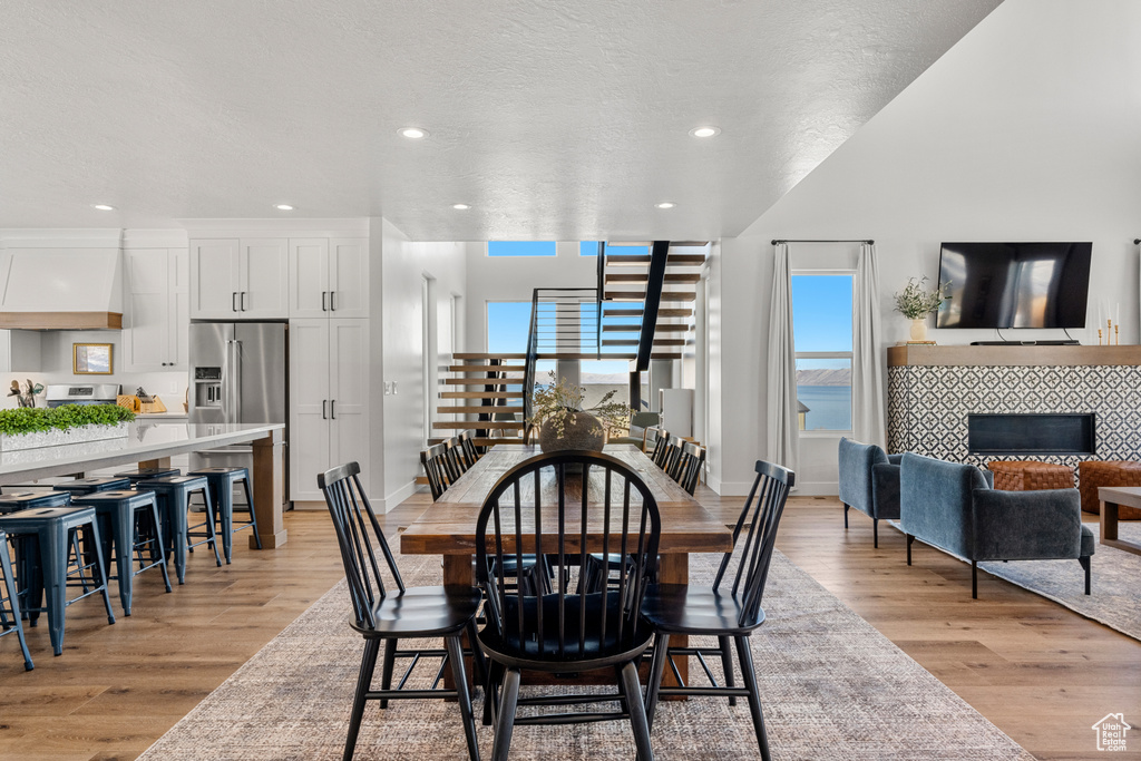 Dining space with recessed lighting, stairs, a tiled fireplace, and light wood-style floors