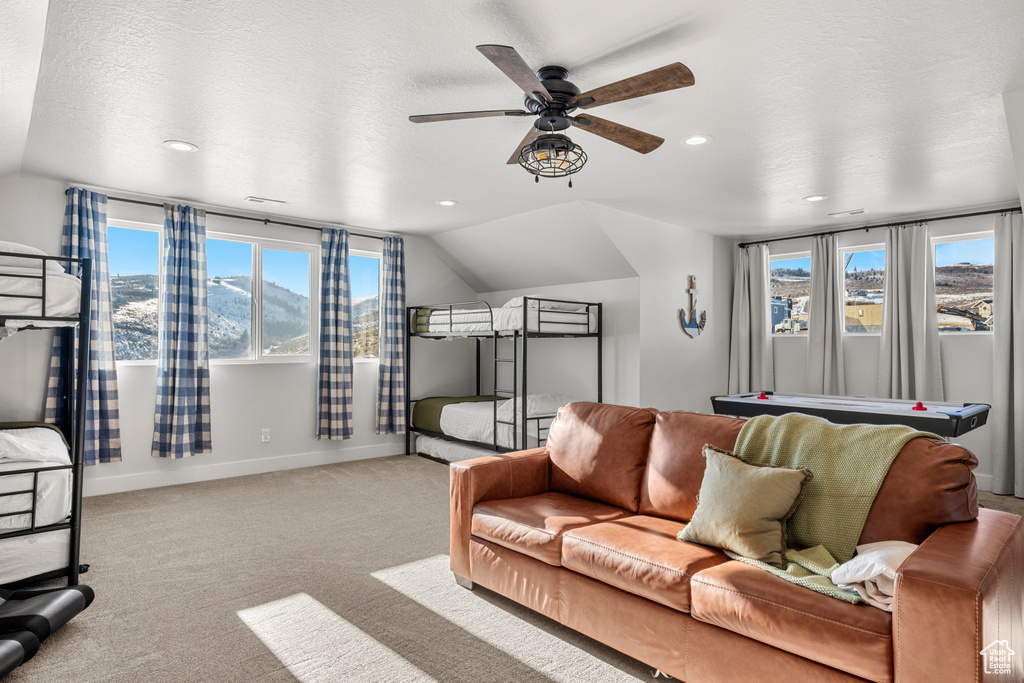 Living area featuring baseboards, a ceiling fan, carpet floors, and vaulted ceiling