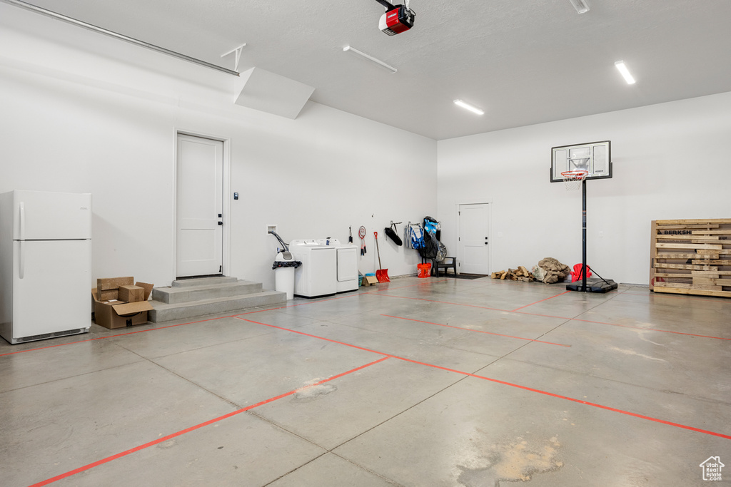 Garage featuring freestanding refrigerator, a garage door opener, and independent washer and dryer