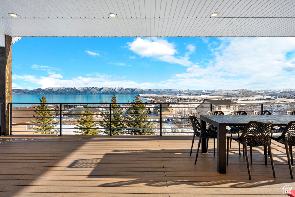 Wooden deck with outdoor dining area and a water and mountain view