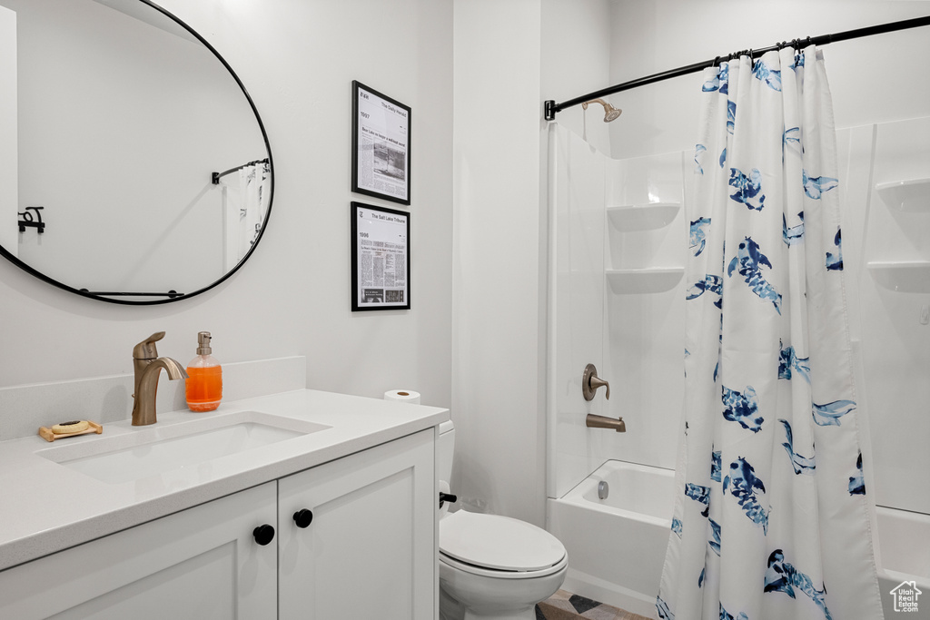 Bathroom featuring toilet, shower / bathtub combination with curtain, and vanity