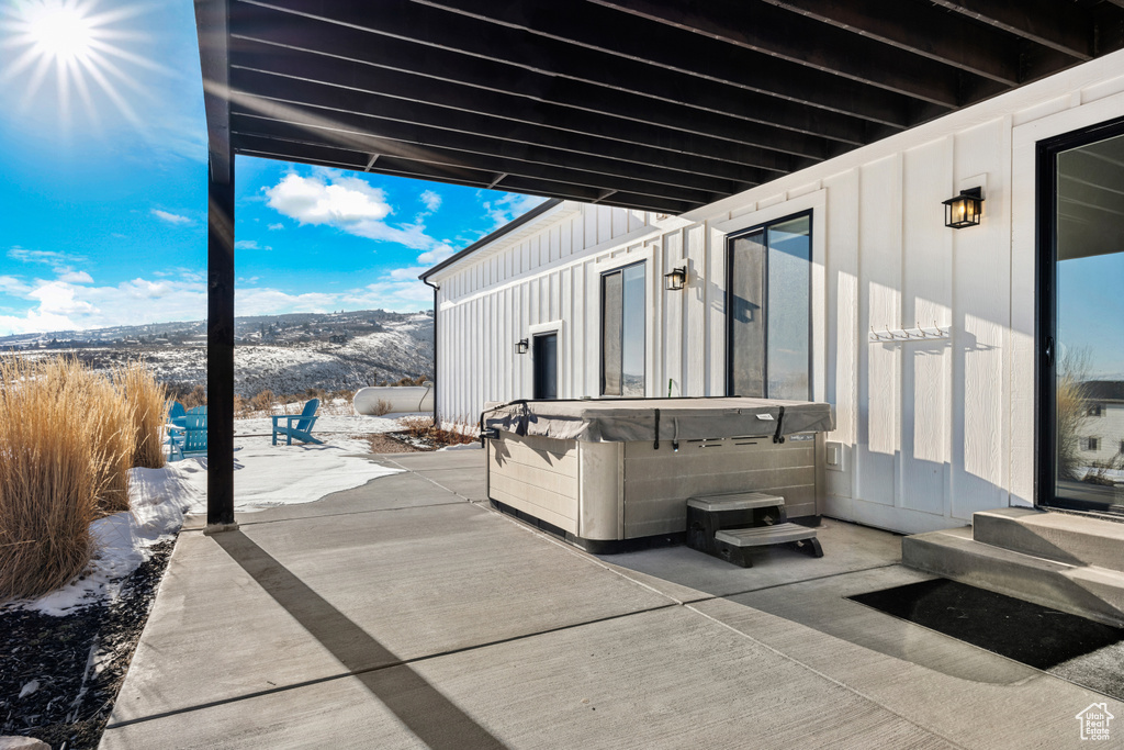 View of patio with a hot tub and a mountain view