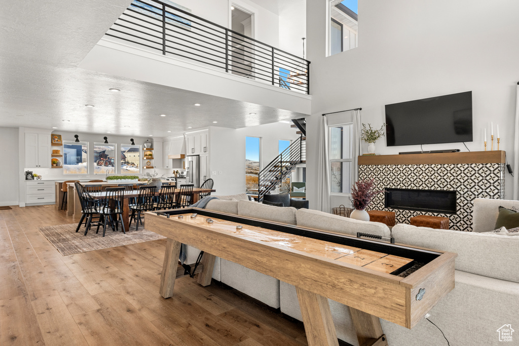 Living room with a tiled fireplace, stairs, and light wood-style flooring