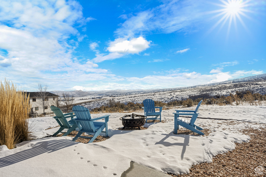 Snow covered patio with a fire pit and a mountain view