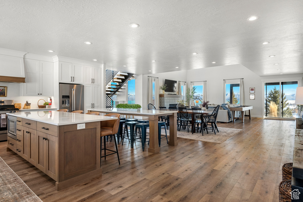 Kitchen featuring a kitchen breakfast bar, a large island, wood finished floors, stainless steel appliances, and recessed lighting