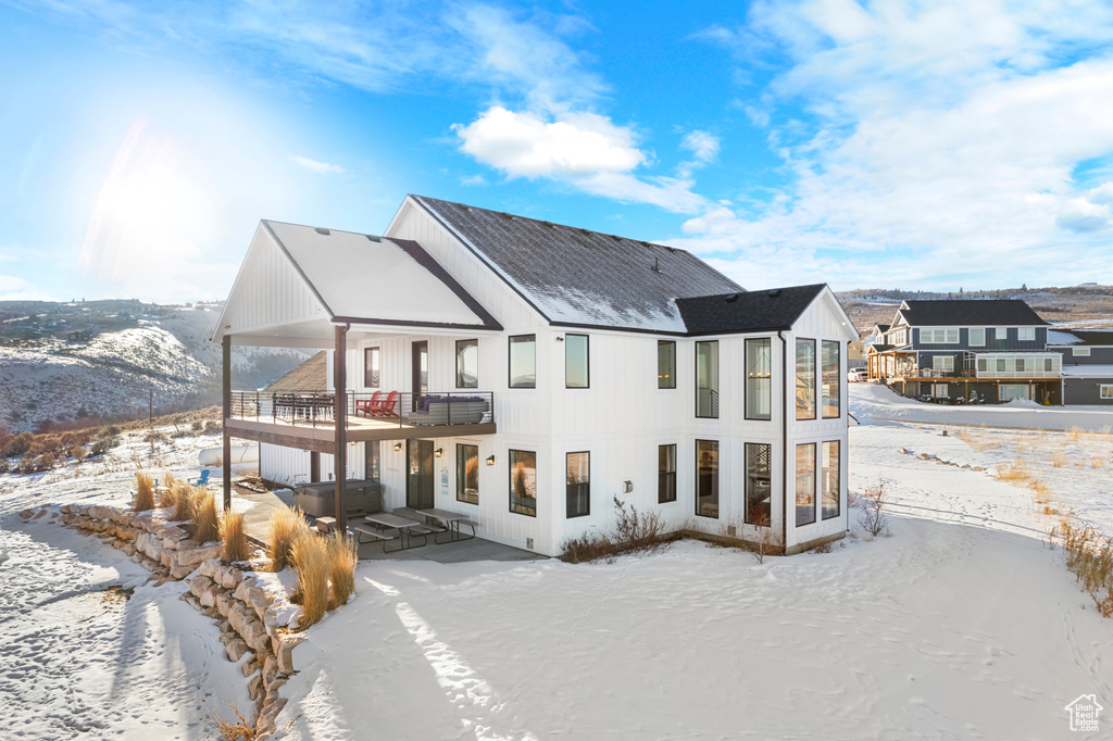 Snow covered back of property featuring a patio and a balcony