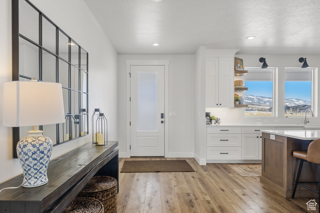 Interior space featuring recessed lighting, baseboards, light wood finished floors, and a textured ceiling