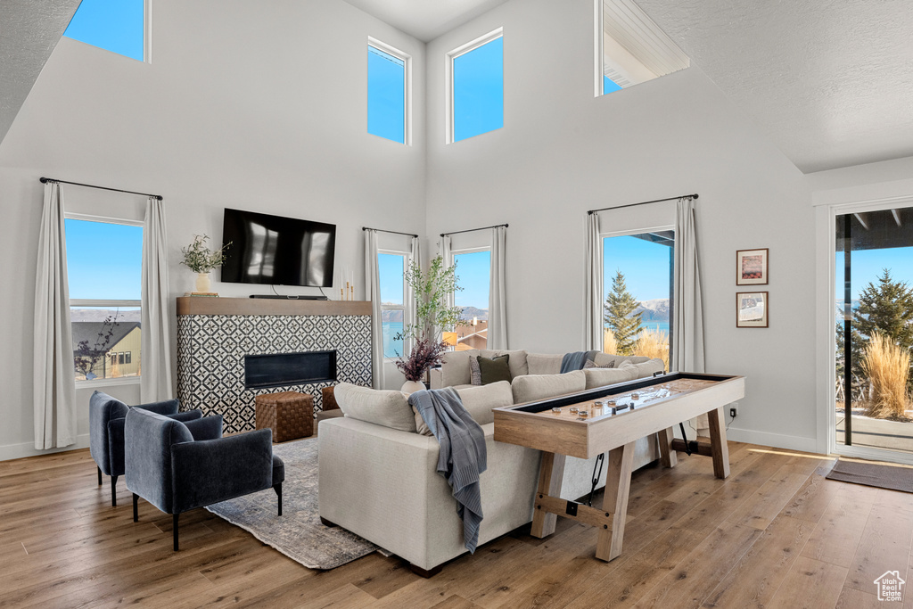 Living room featuring a fireplace, a high ceiling, baseboards, and light wood-style floors