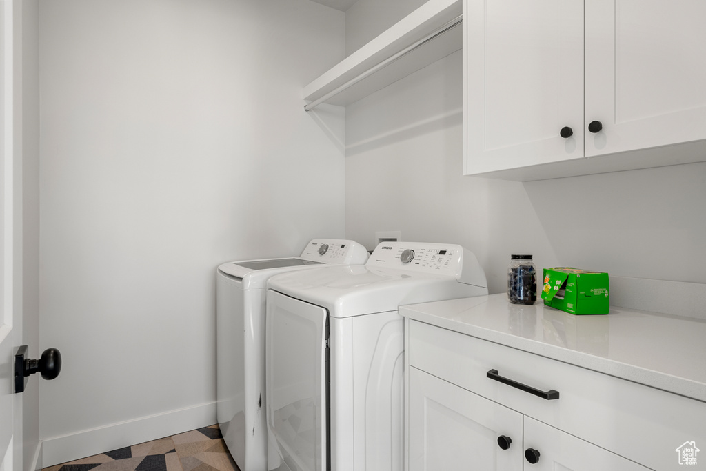Clothes washing area with baseboards, washer and clothes dryer, cabinet space, and tile patterned floors