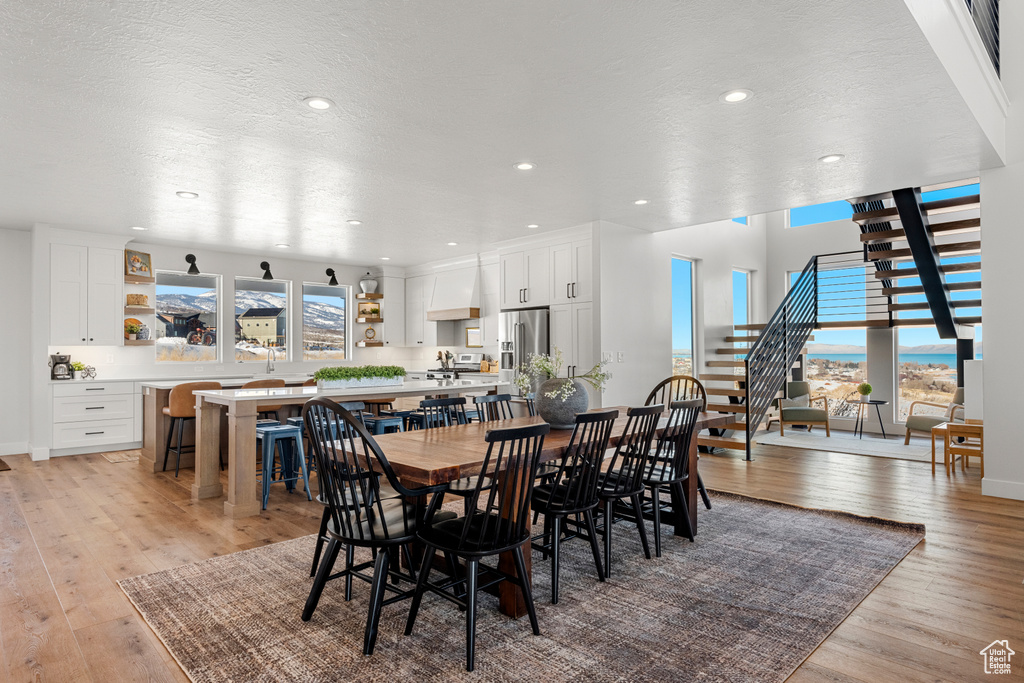 Dining area featuring a textured ceiling, visible vents, stairway, light wood-style floors, and recessed lighting